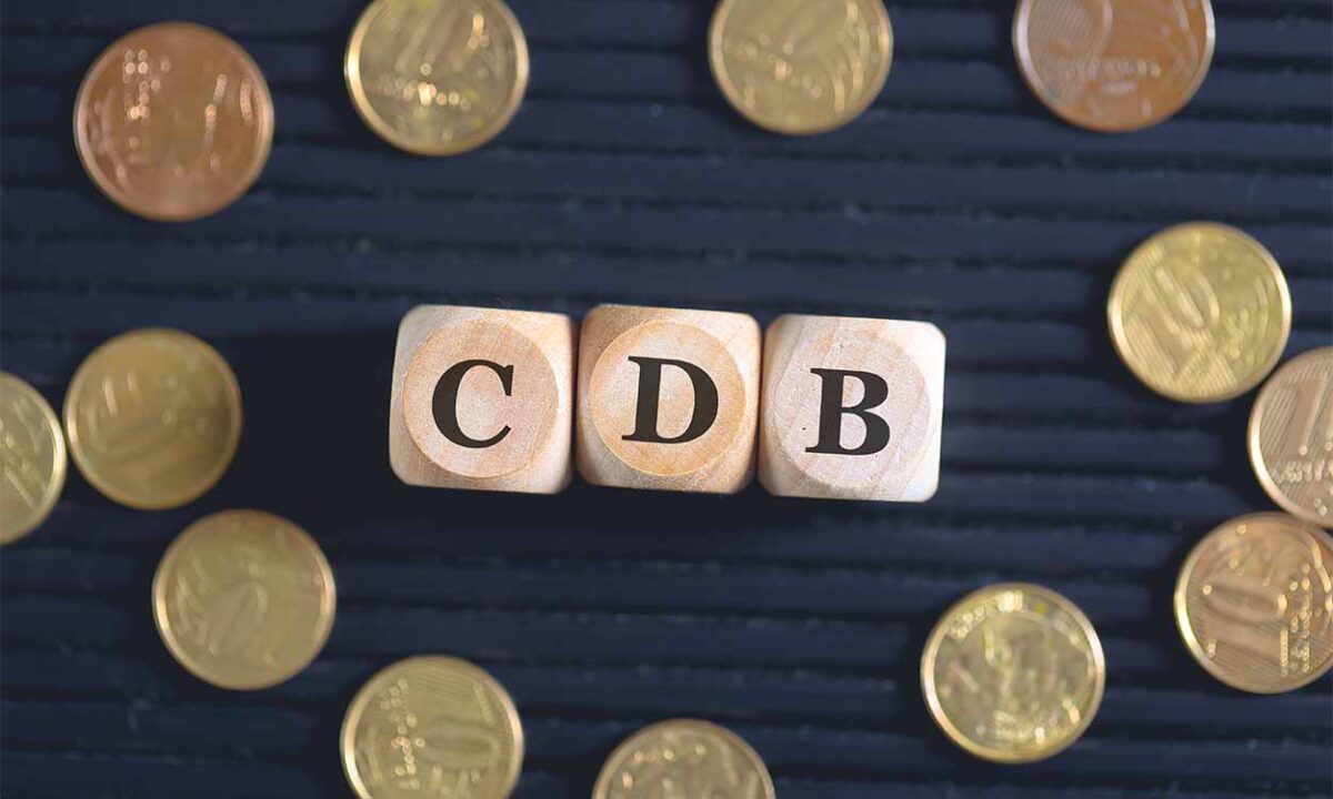 Blocos de madeira com letras formando a sigla "CDB" e moedas espalhadas ao redor