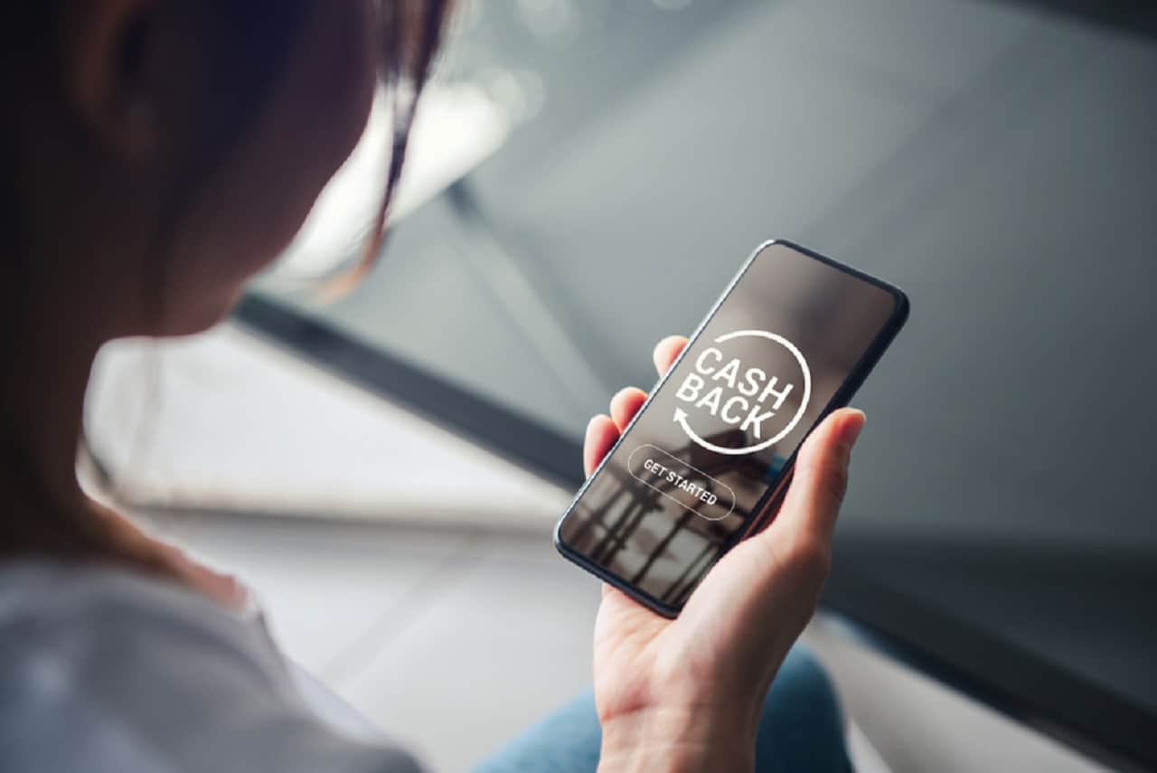 Imagem de uma pessoa segurando um celular com a tela focada na palavra cashback