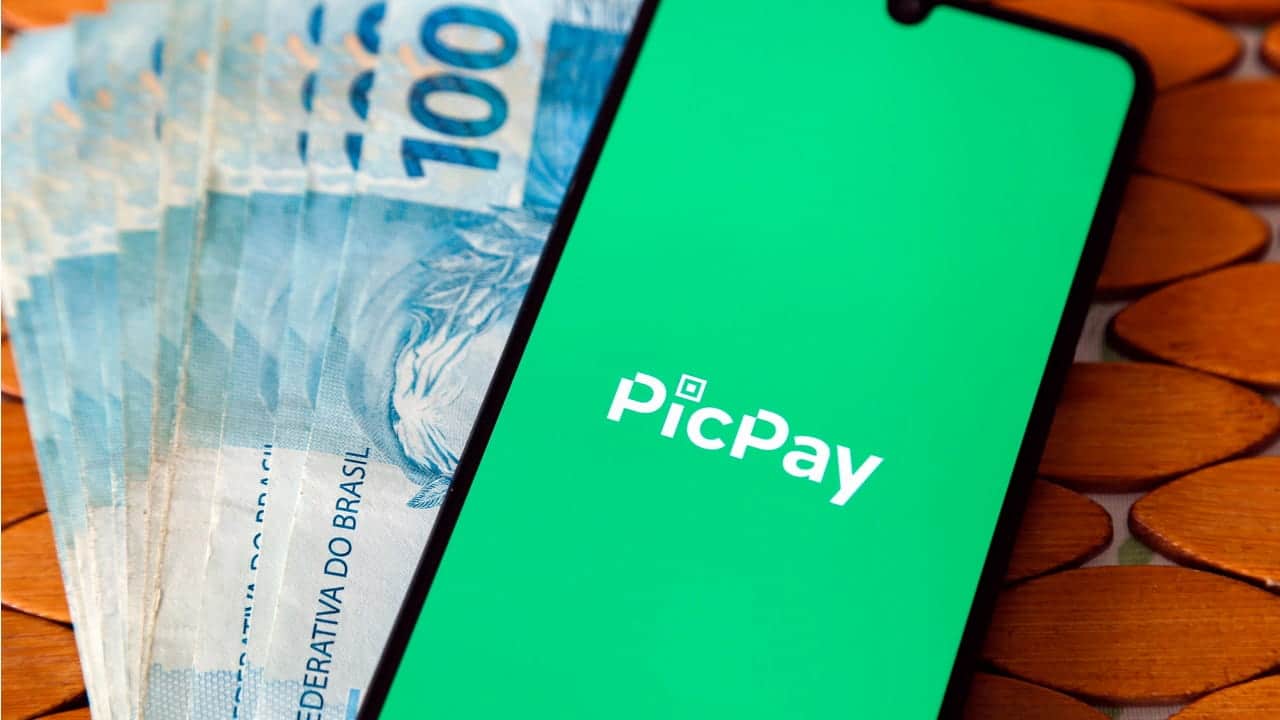Dinheiro e celular com PicPay aberto
