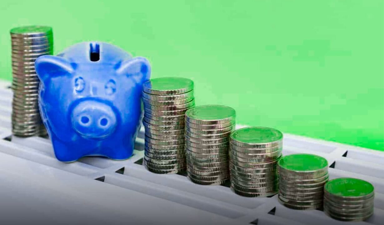Imagem de uma pilha de moedas com um cofre no formato de porco no meio.