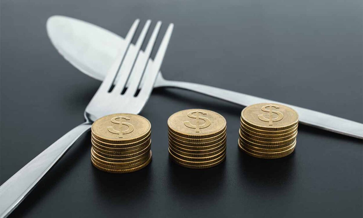 Garfo e colher, com pilhas de moedas ao lado