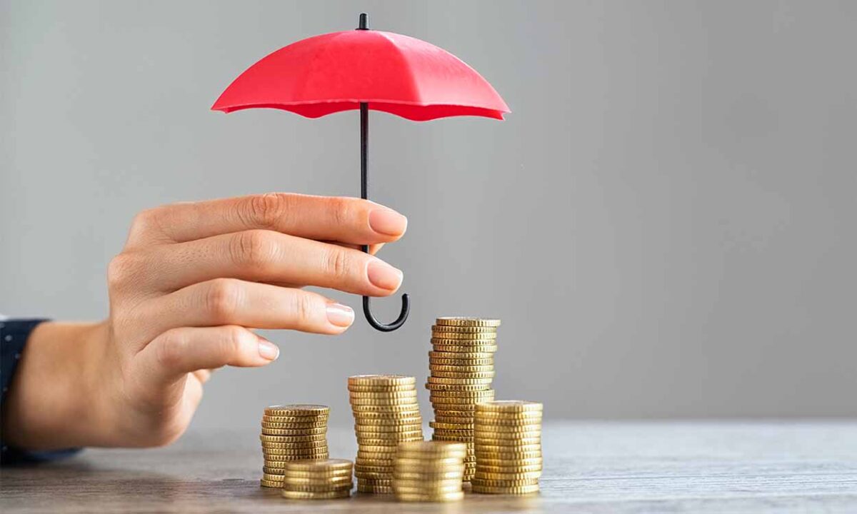 Mão segurando guarda-chuva sobre pilha de moedas