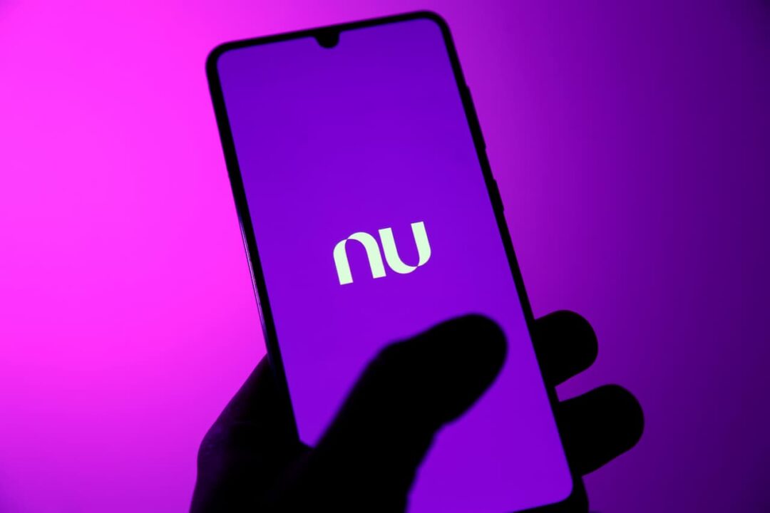 Mão segurando celular com tela inicial do app Nubank