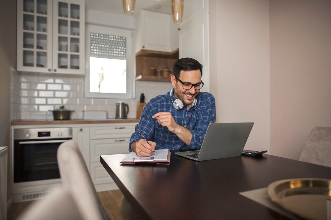 Homem sorrindo, trabalhando em home office.