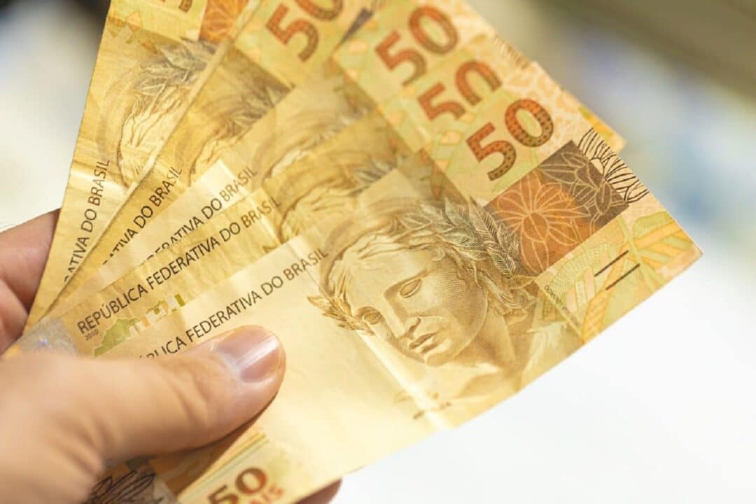Imagem de uma pessoa segurando notas de R$50