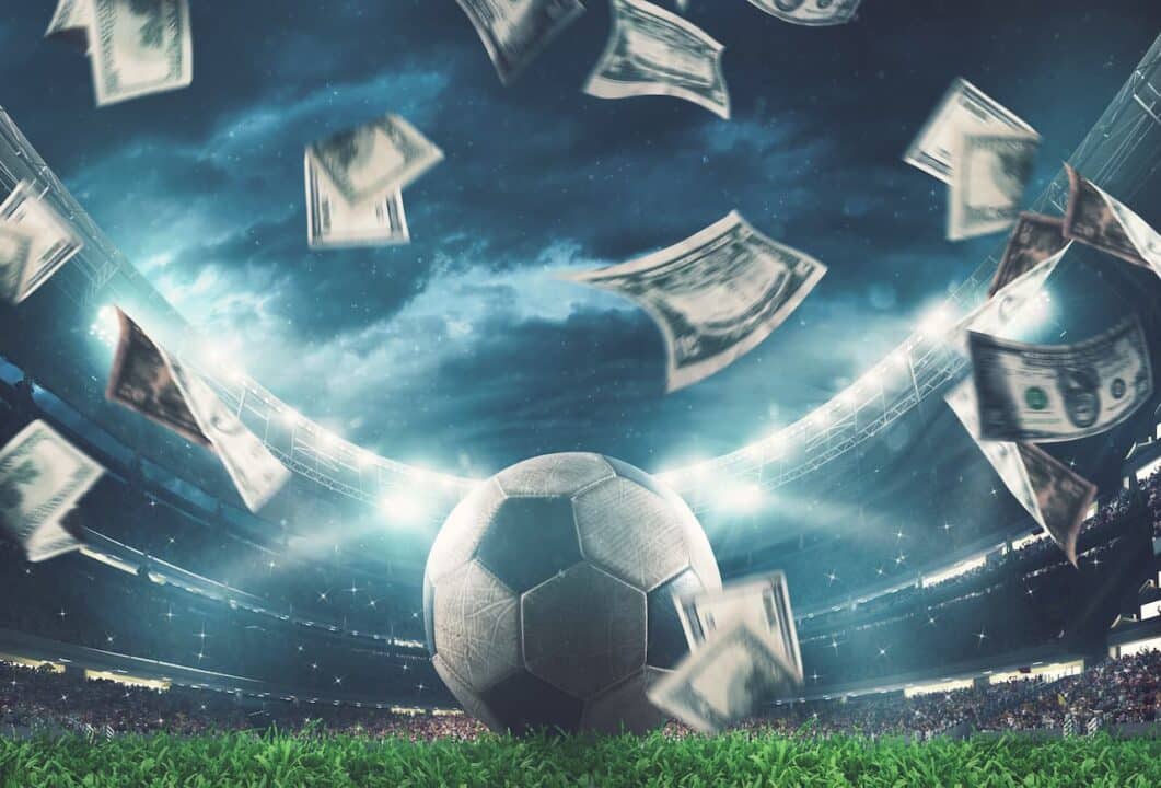 Campo de futebol, bola e cédulas no ar
