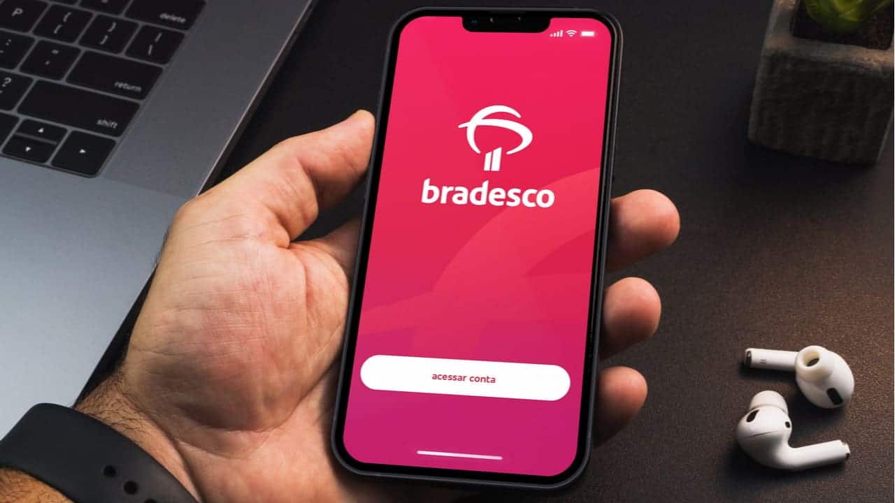 Mão segurando celular que mostra tela inicial do aplicativo Bradesco