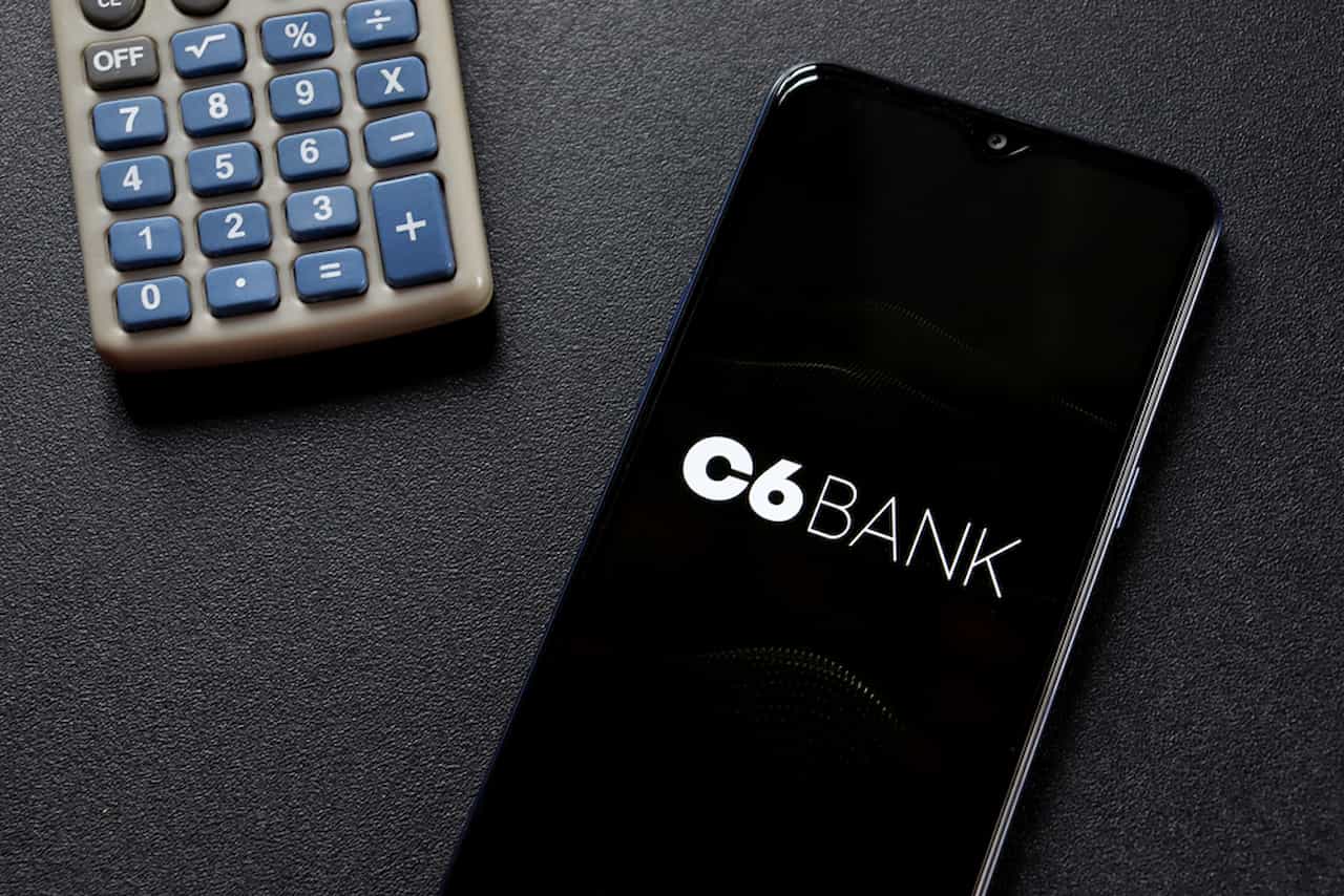 Ao lado de uma calculadora, celular exibe o aplicativo do C6 Bank