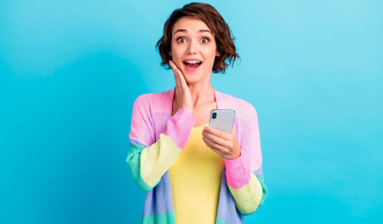 Mulher segurando celular com expressão de surpresa