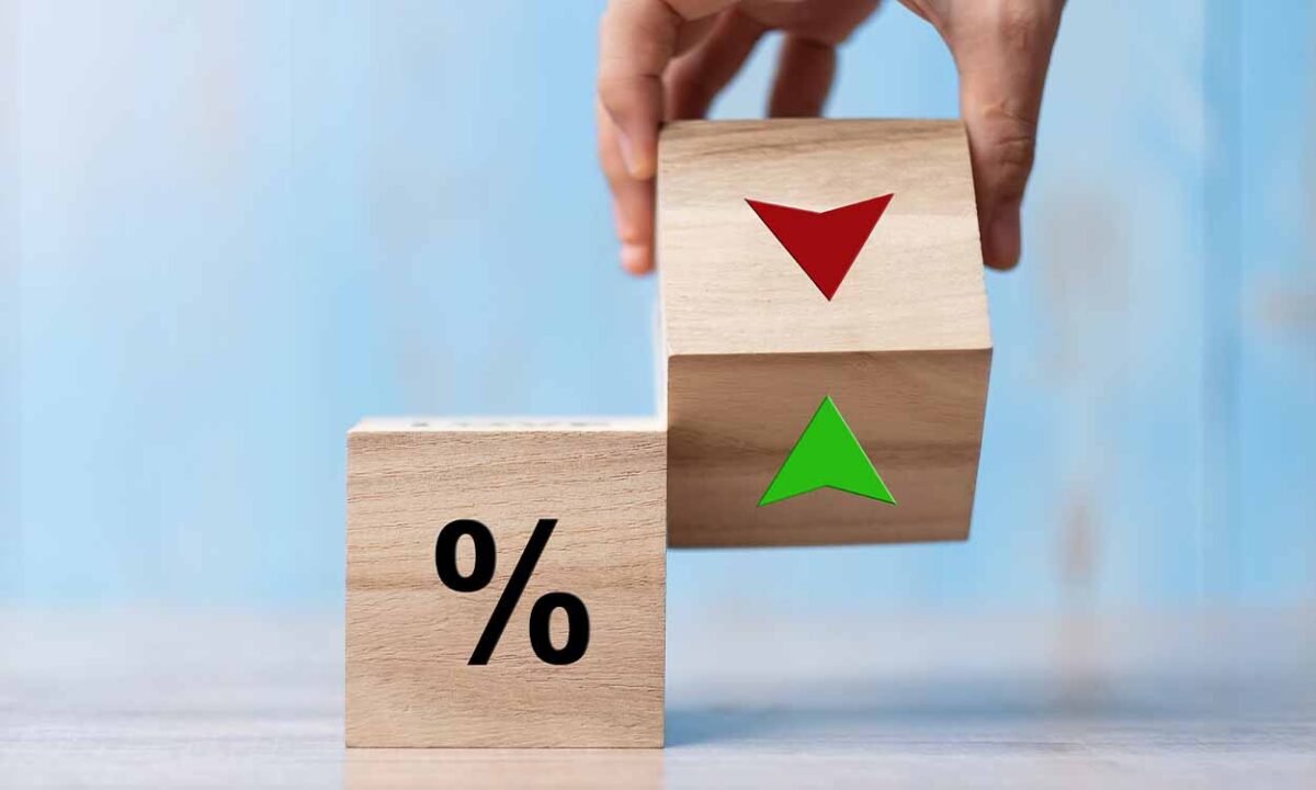 Dois cubos de madeira com símbolo de percentual de setas em vermelho e verde, simbolizando o corte na taxa básica de juros que o Copom decidiu em última reunião.