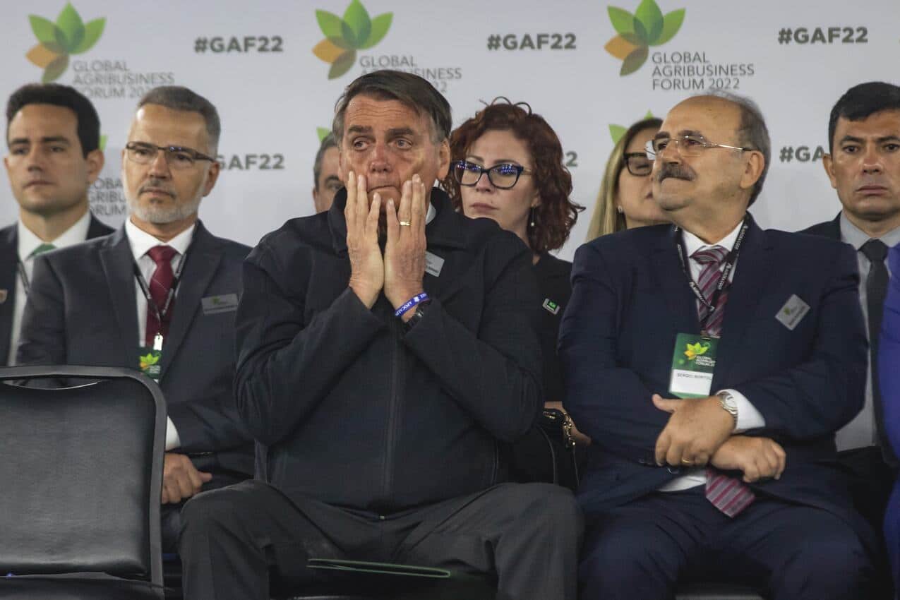 Jair Bolsonaro passando as mãos no rosto com cara de preocupado durante evento.
