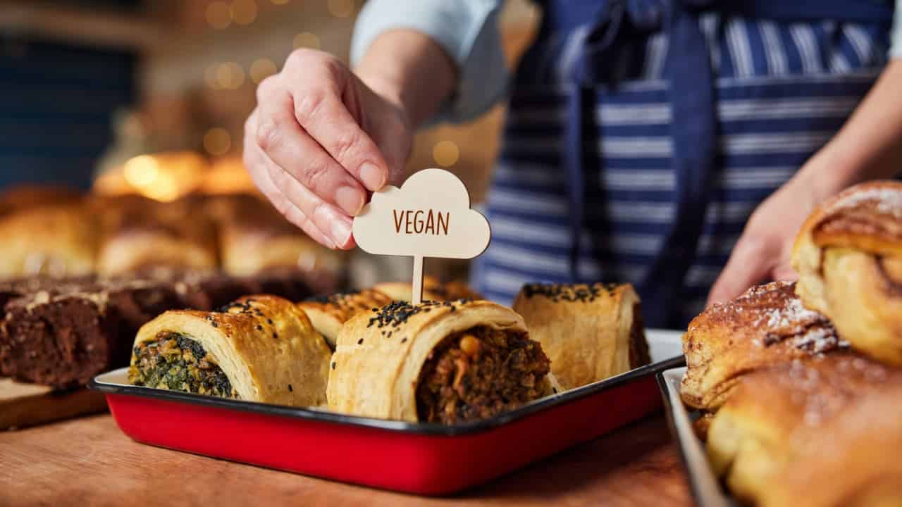 Assistente de vendas em padaria enquanto coloca rótulo vegano em salgado recém-assado