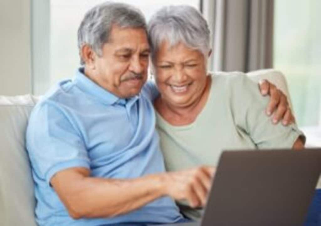 Casal de idosos felizes enquanto mexem em computador