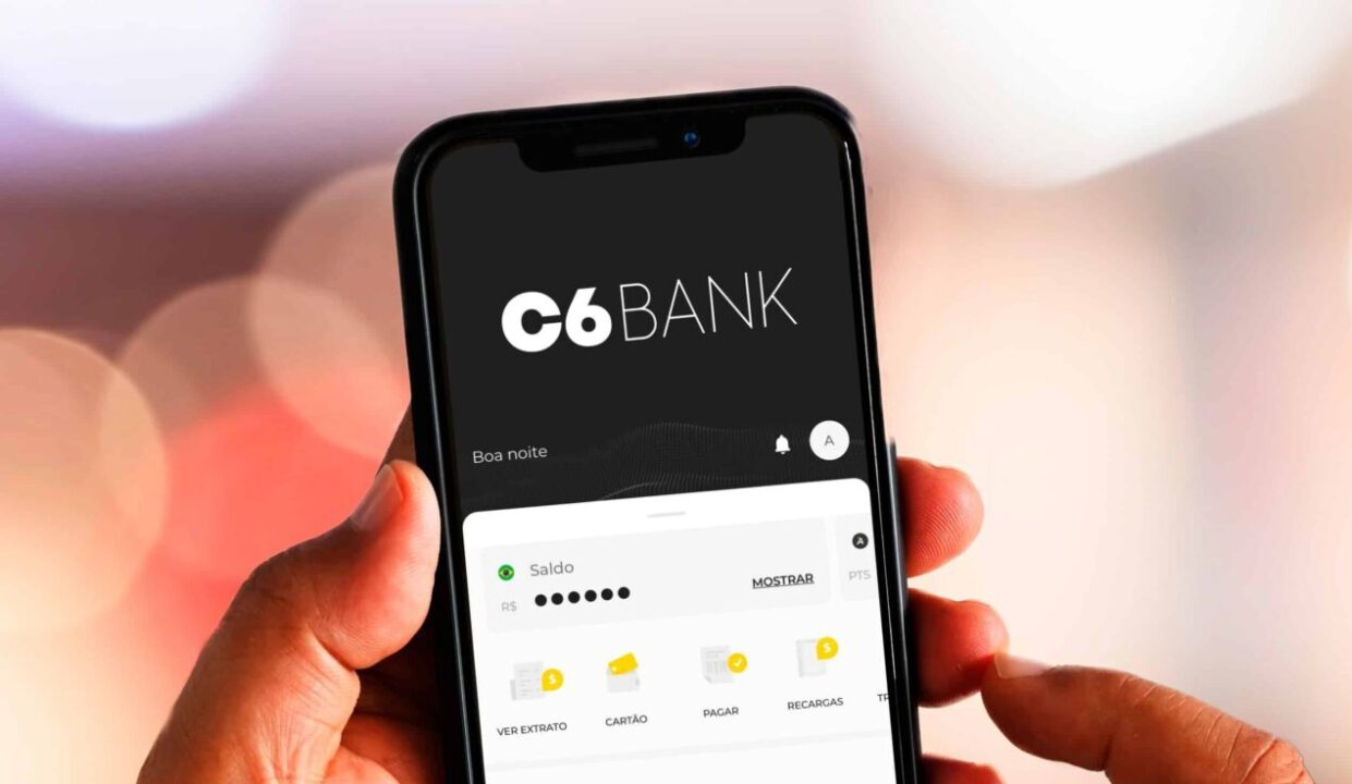 Mão segurando smartphone com o aplicativo do C6 Bank aberto
