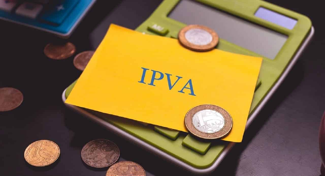 Imagem de um cartão com a sigla IPVA sobre uma calculadora com duas moedas de 1 real.
