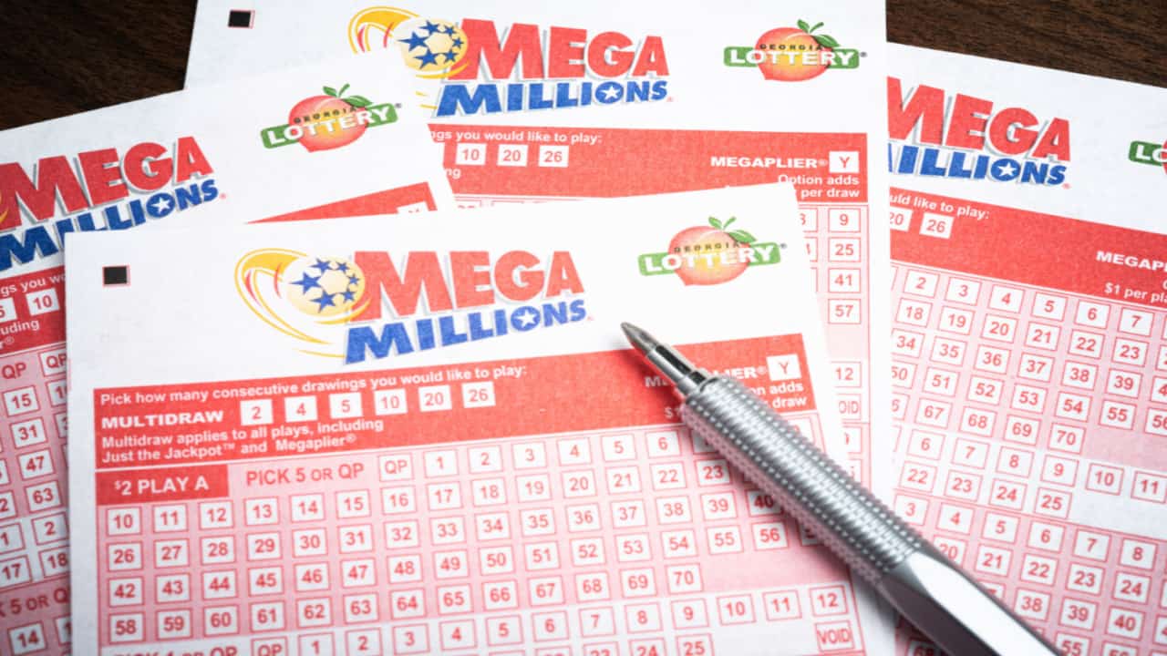 bilhetes de loteria da Mega Millions e uma caneta em cima