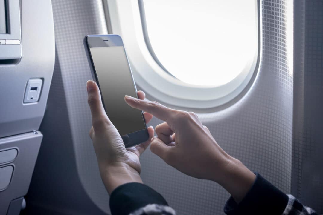 Mãos mexendo no celular dentro de um avião