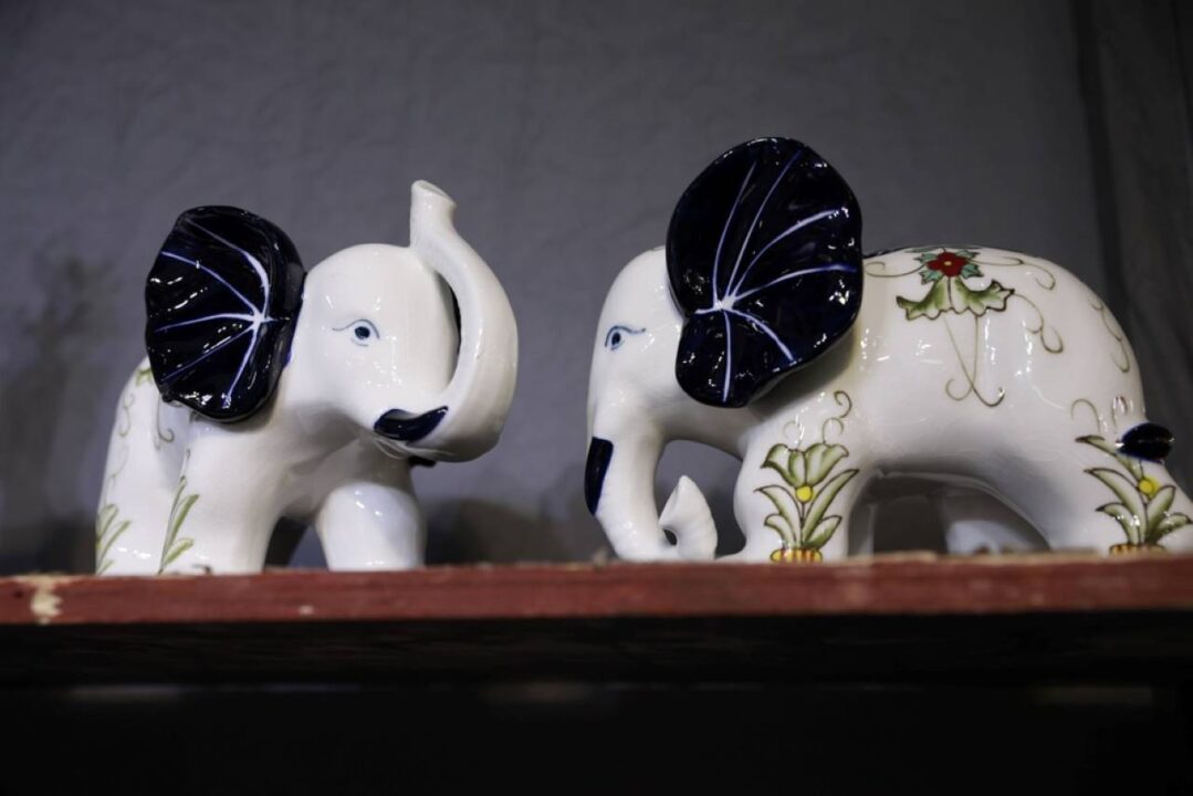 dois enfeites de elefante em cima de uma prateleira