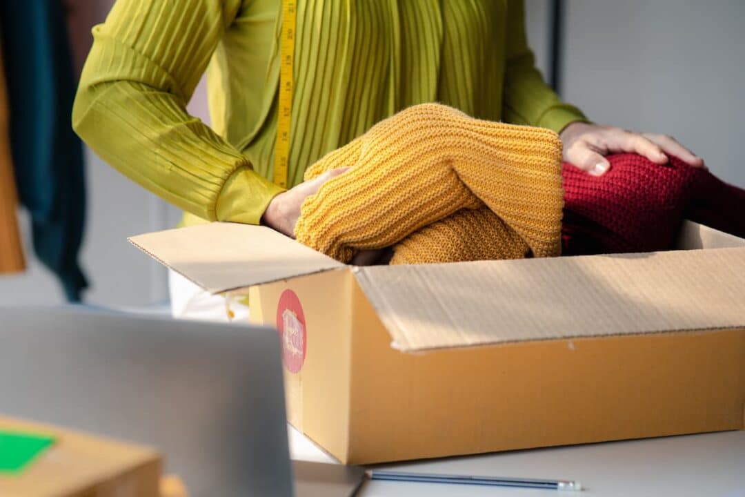 Mulher empacotando roupas para envio por empresa de moda.