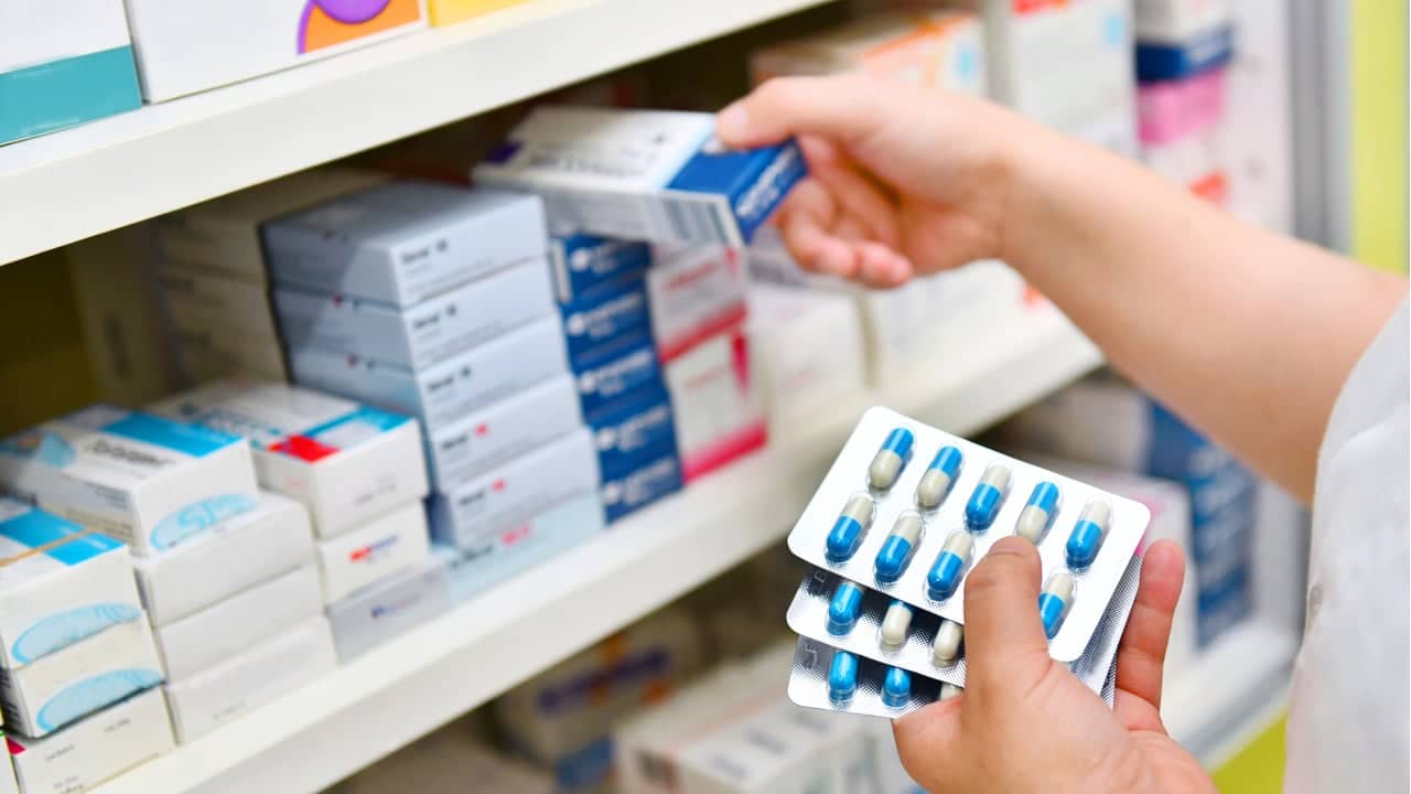 farmacêutica retirando medicamentos da prateleira de uma farmácia