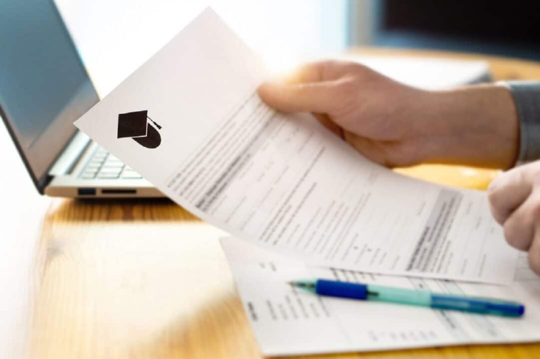 Imagem de uma pessoa segurando um documento de faculdade