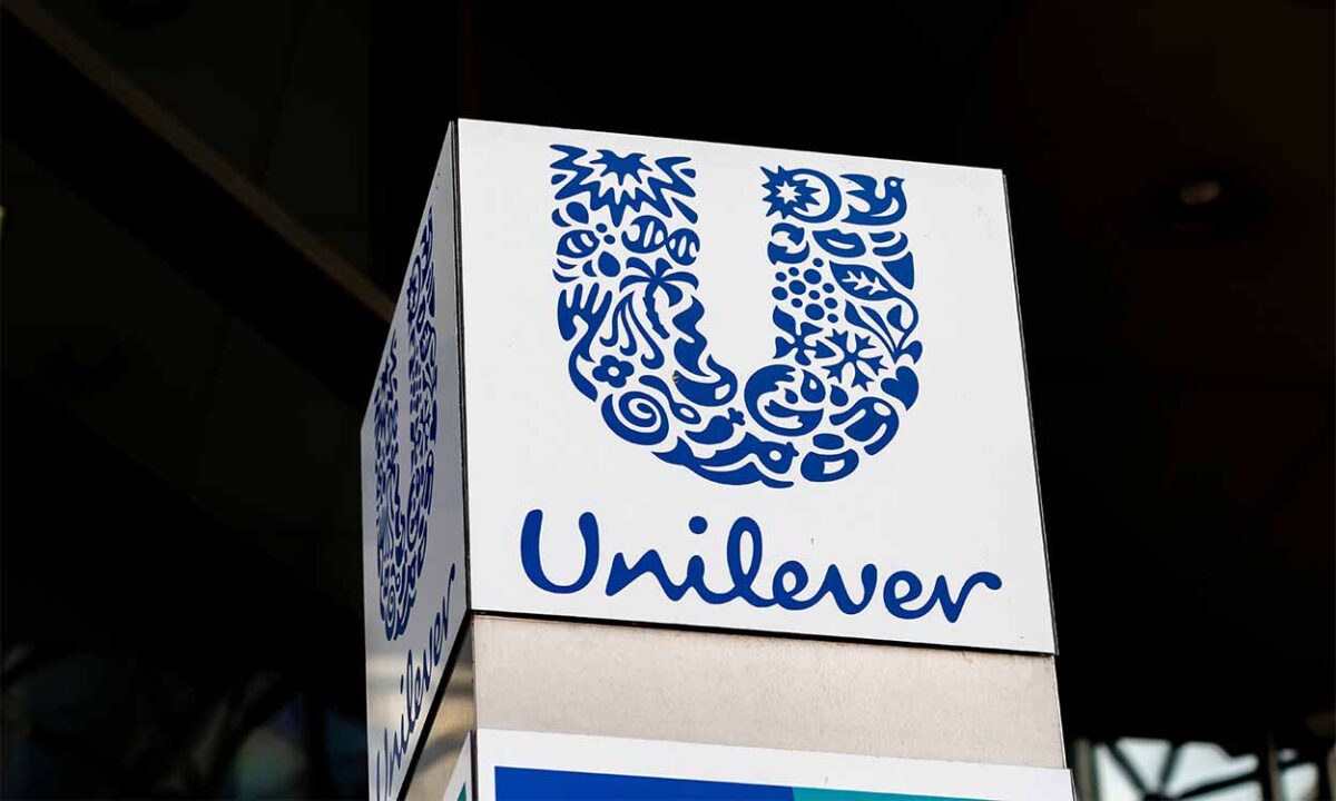 Logotipo da Unilever em uma estrutura que provavelmente está em frente a uma fachada da empresa. A estrutura tem mais de dois lados e em cada um deles, ao que tudo indica, está a logo da empresa