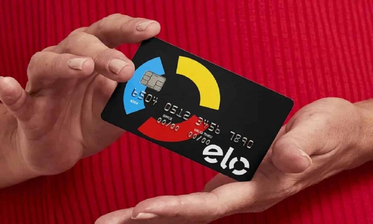 Mãos segurando um cartão com a bandeira Elo