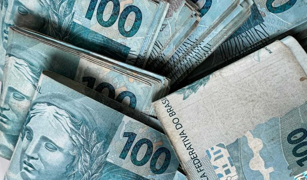 Maço de notas de R$ 100 espalhados em uma superfície