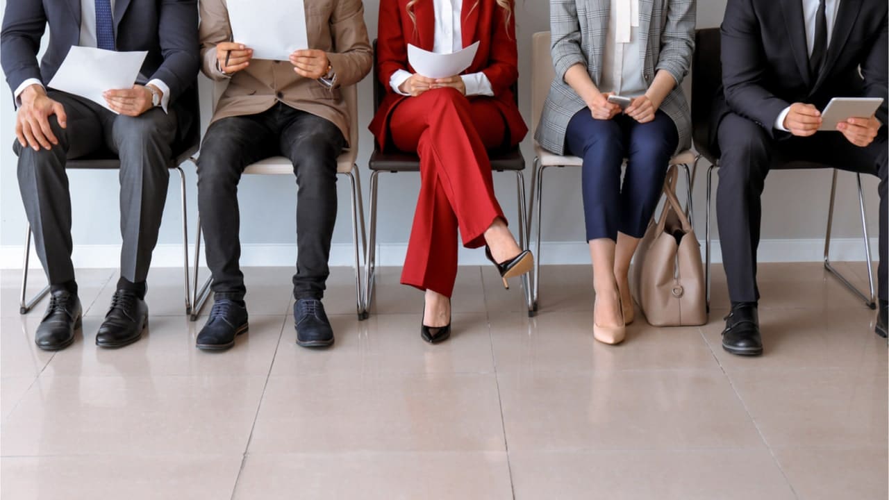 Pessoas sentadas aguardando entrevista de emprego