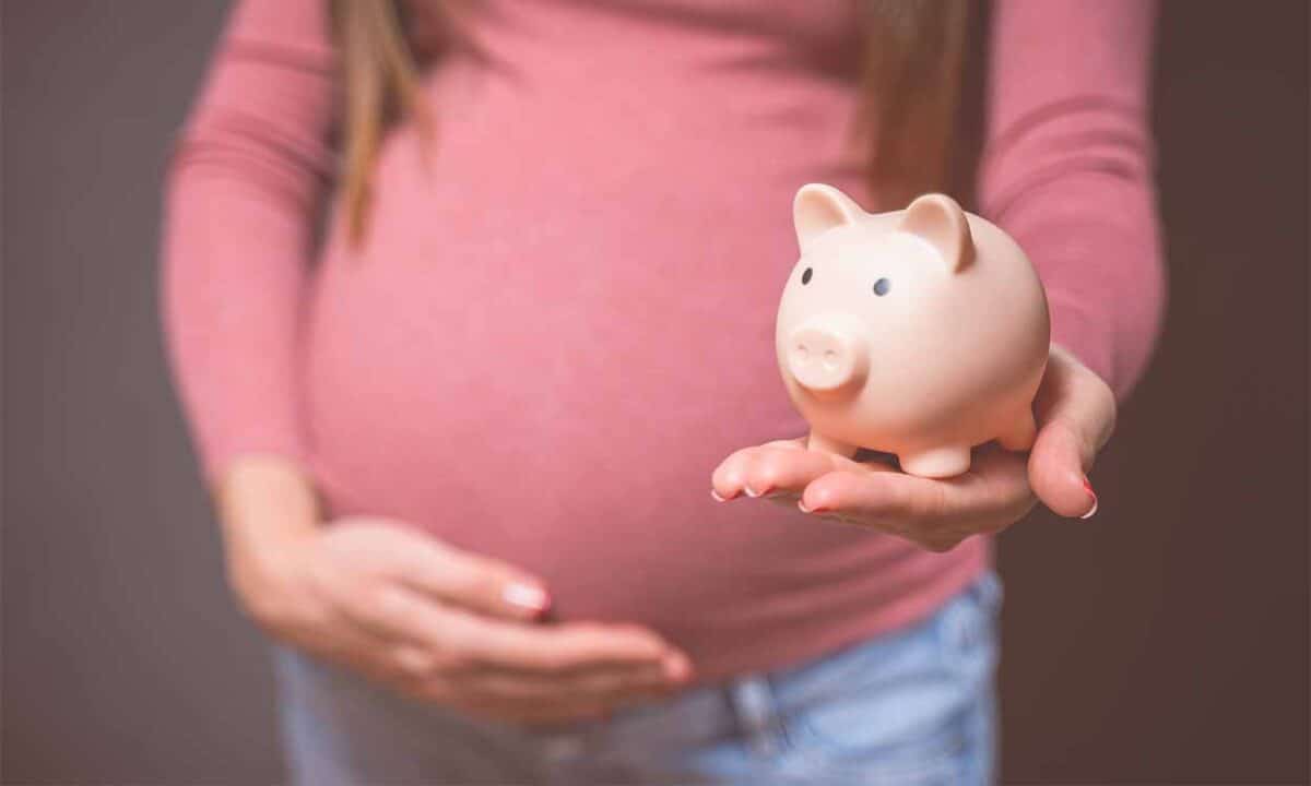 Mulher grávida segurando um porquinho de moeda