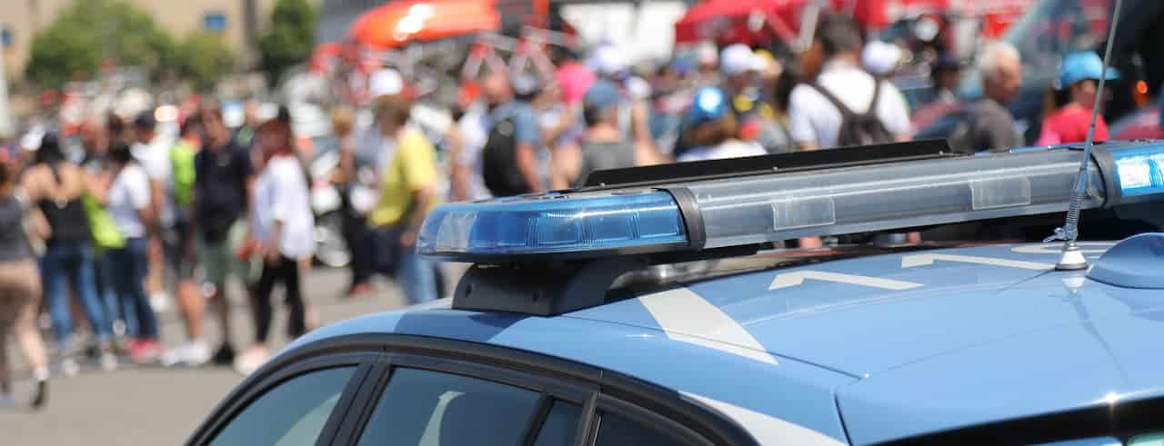 Viatura da polícia e ao fundo manifestação de pessoas
