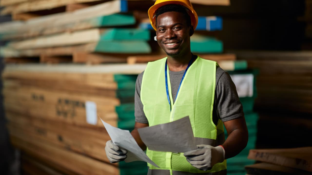 trabalhador afro-americano sorri enquanto olha para a câmera durante expediente de trabalho em armazém de distribuição