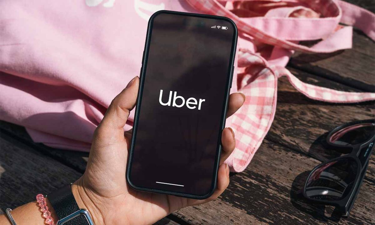 Mão segurando celular com app da Uber