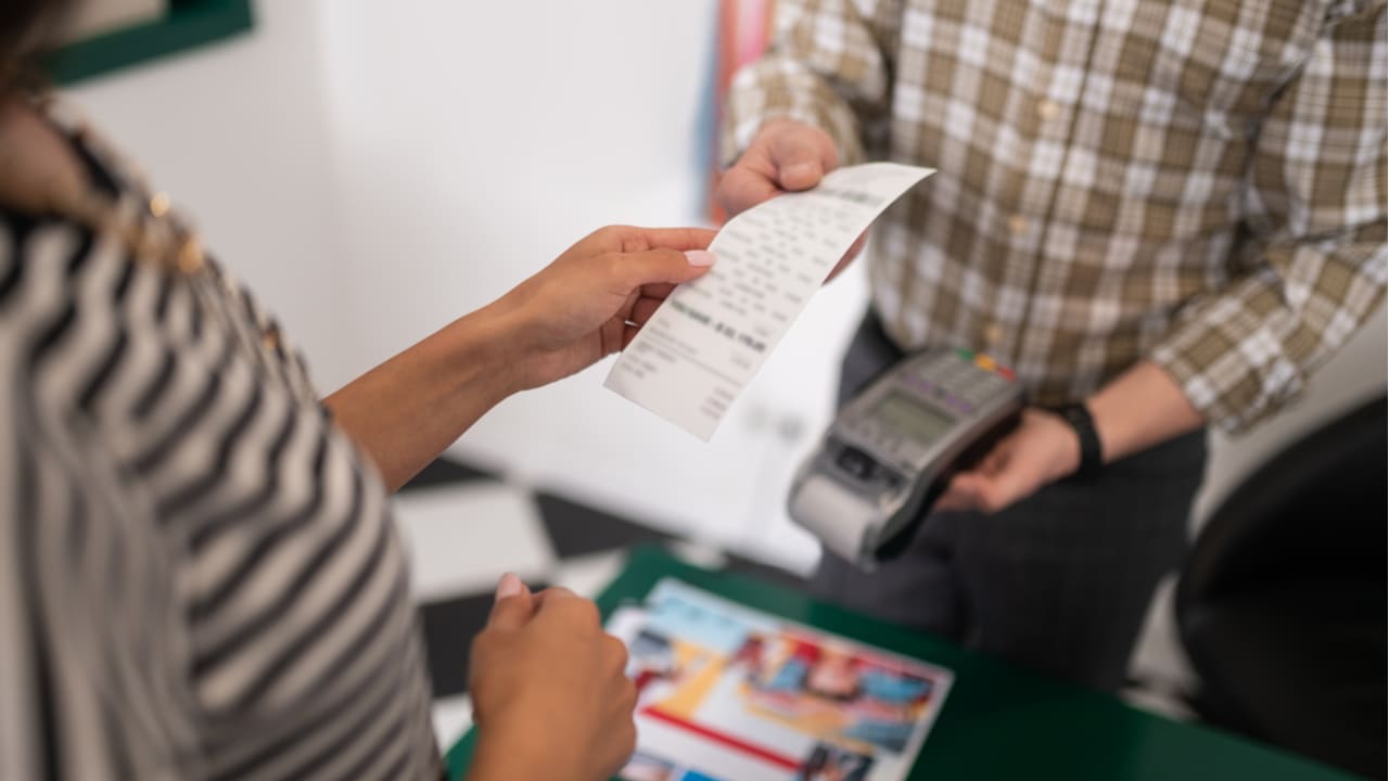 Imagem de um vendedor entregando uma nota fiscal para um consumidor