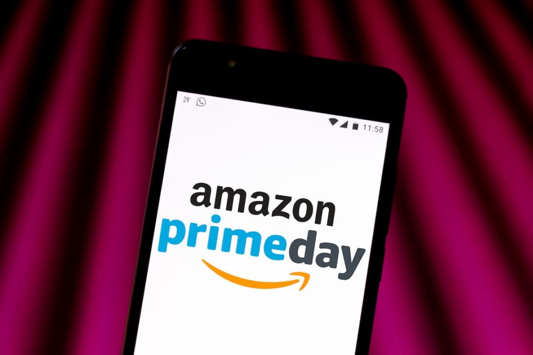 Imagem Amazon Prime Day promocional no celular de cliente com fundo de cortinas