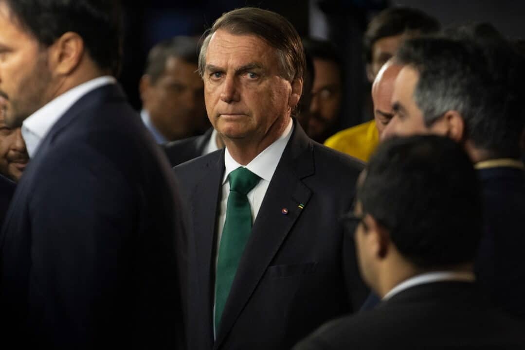 Jair Bolsonaro parado com pessoas ao redor