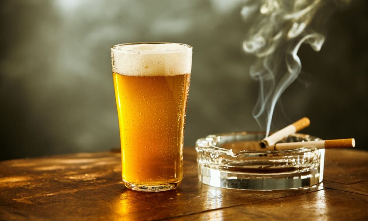 Cerveja e cigarro em cima de uma mesa