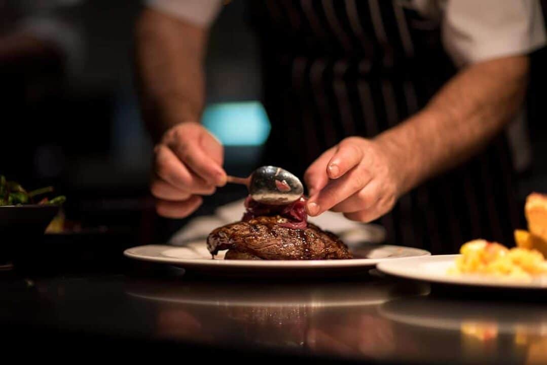 Na imagem, chef montando o prato de carne.