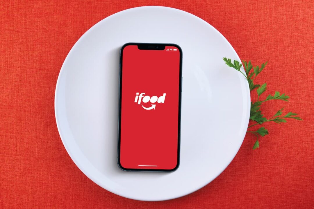 Aplicativo de popular empresa iFood, em celular sobre prato branco