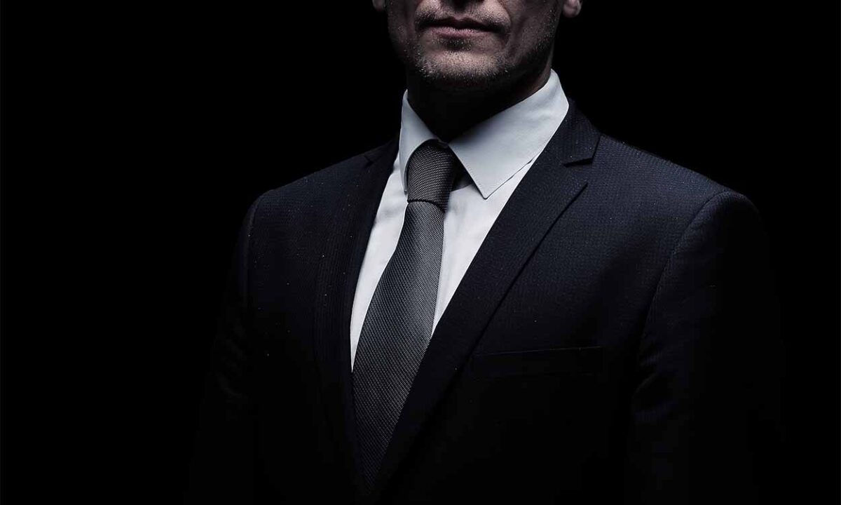 Na imagem, um homem vestindo um terno escuro.