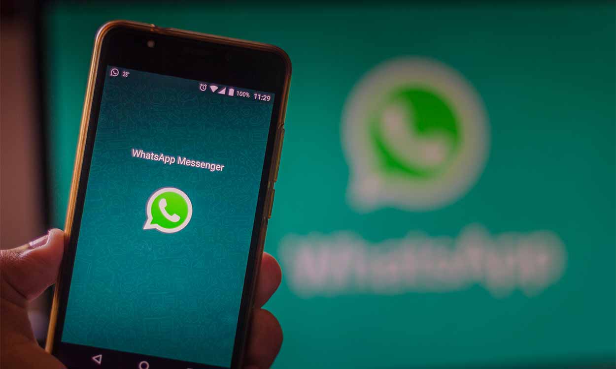 Celular com aplicativo do WhatsApp e televisão com logo do app atrás