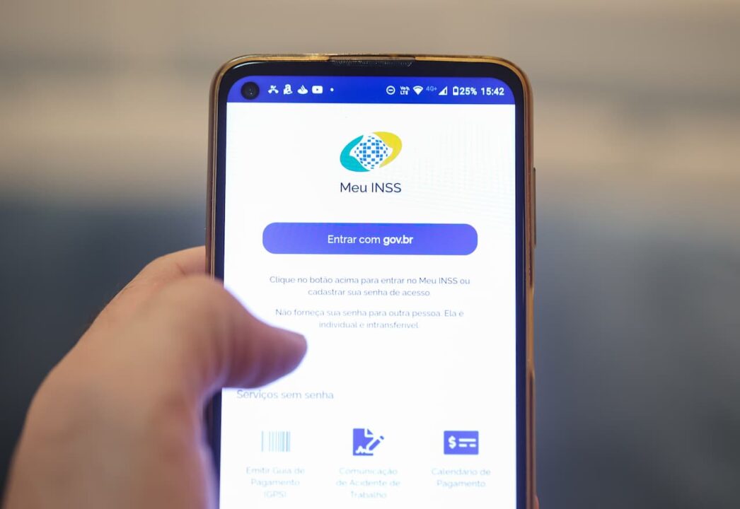mão segurando celular com INSS