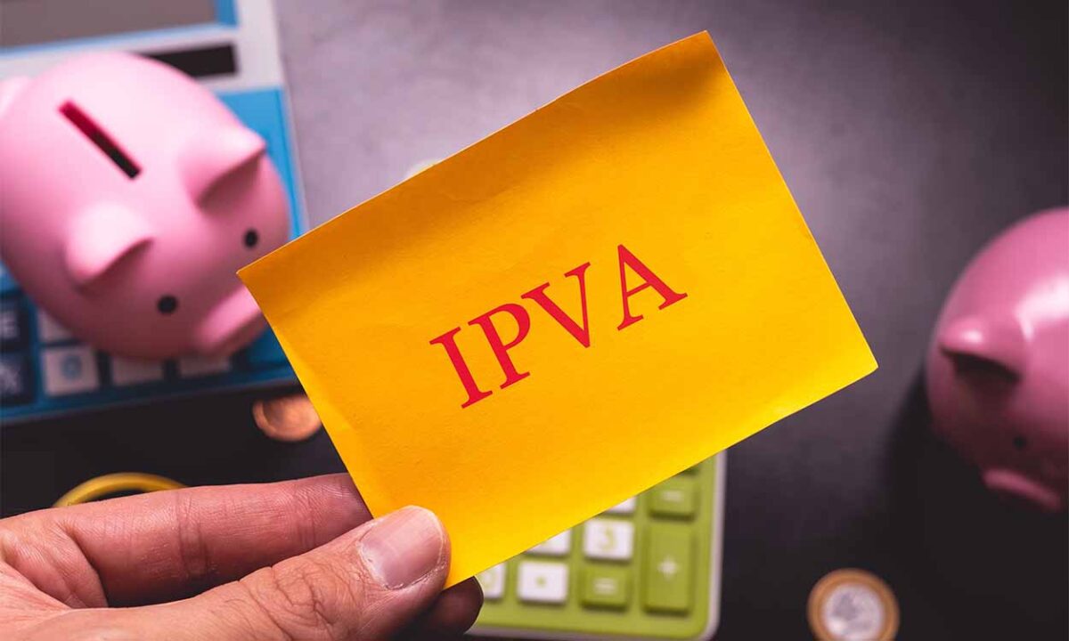 Post it amarelo com a palavra "IPVA" com calculadoras e cofrinhos no background.