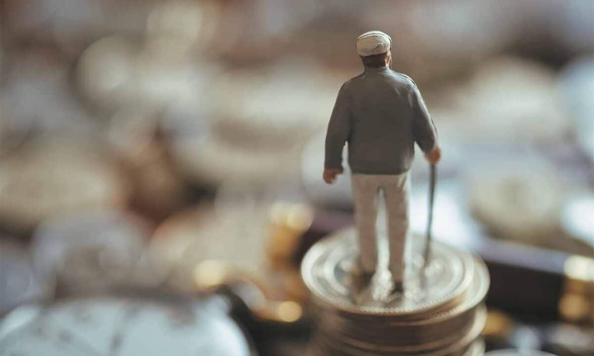 Miniatura de plástico de um idoso em cima de várias moedas
