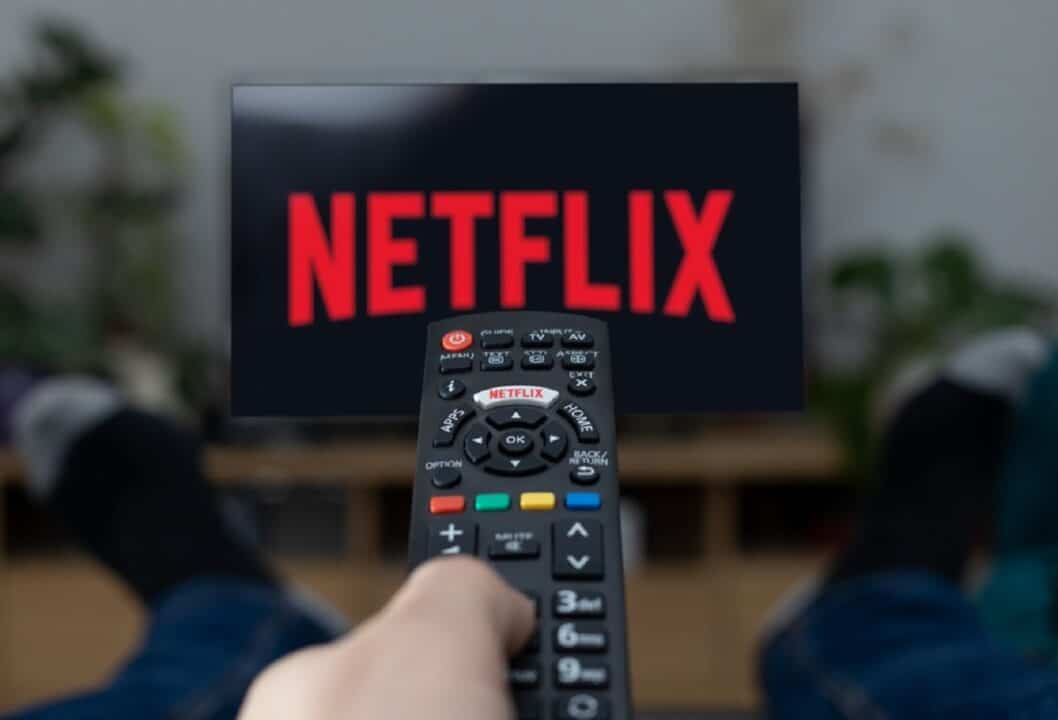 Imagem de uma pessoa apontando um controle para a TV com a logo da Netflix