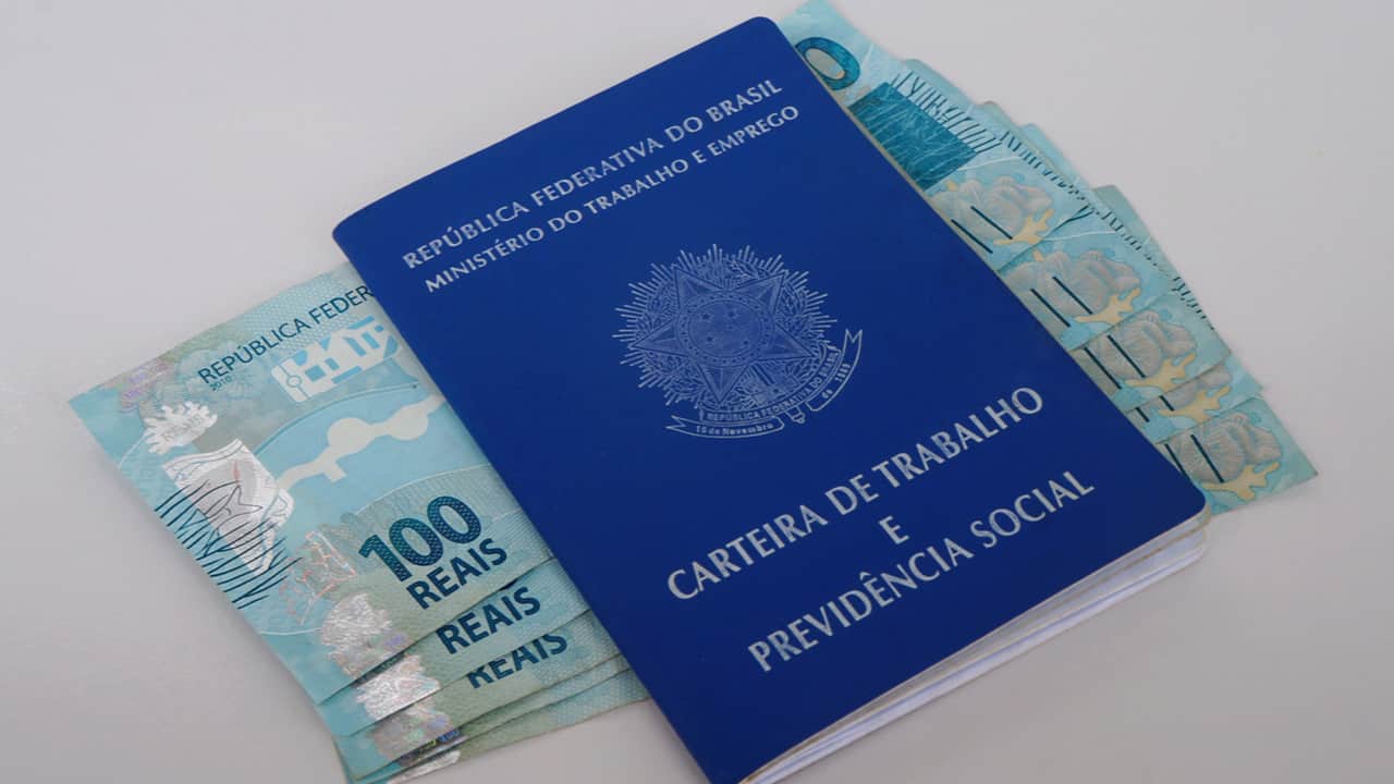 Carteira de Trabalho em cima de notas de 100 reais