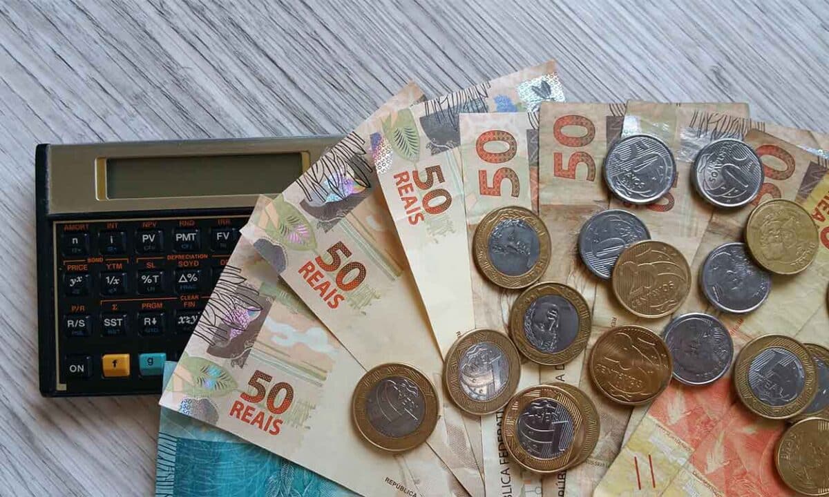 várias cédulas de 50 reais e moedas ao lado de uma calculadora. apagão fiscal