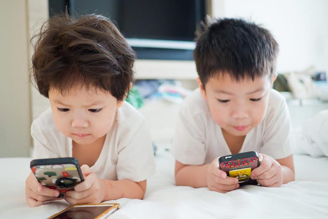 Duas crianças utilizando a internet no celular.