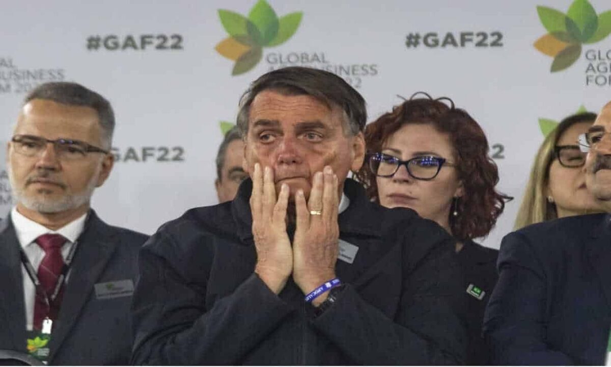 Jair Bolsonaro passando as mãos no rosto com cara de preocupado durante evento.