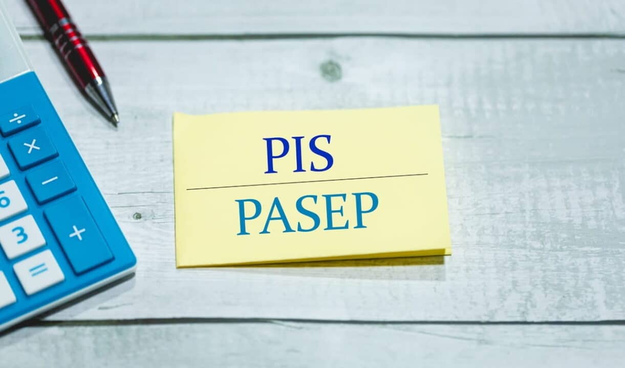Bloco de anotações com as siglas PIS/Pasep ao lado de uma caneta e uma calculadora. abono salarial